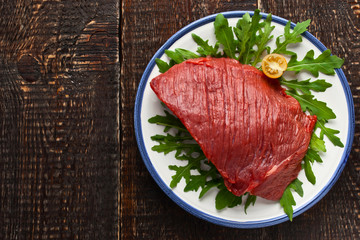 Raw red meat on the plate on the wooden table