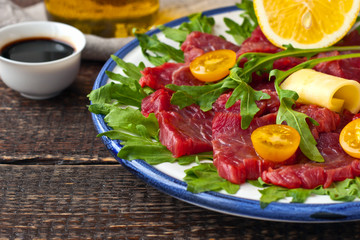 Carpaccio on the white plate on the wooden table