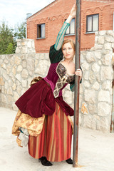 Fototapeta na wymiar Actress in medieval dress standing near a pole outside