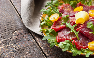Carpaccio on the white plate on the wooden table