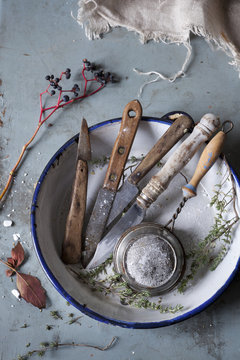 old used kitchen knives and vintage strainer on rustic table