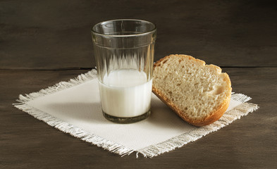Glass of milk and a loaf of fresh bread on the linen napkin