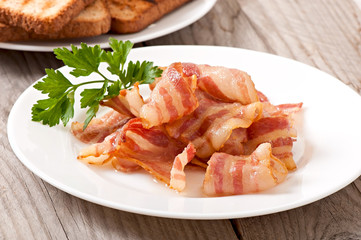 delicious hot fried bacon on a white plate and toast