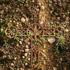 Broken iron rustic crucifix on mossy sand. Abandoned symbol