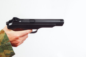 Hand in camouflage uniform with handgun on a white background
