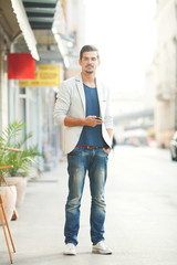 Fototapeta premium Handsome young man using mobile phone on the street