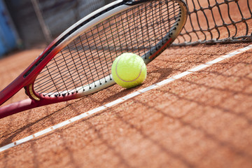 Close up of tennis racquet and ball on the clay tennis court 
