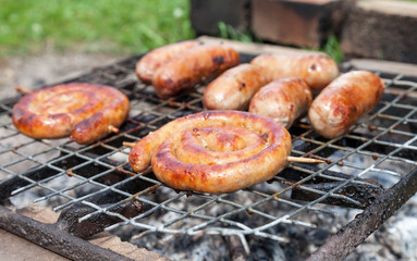 Tasty sausages cooking over the hot coals on a barbecue fire