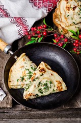 Ukrainian pancakes with meat, greens and onion in iron plate on wooden vintage background