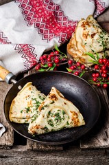 Ukrainian pancakes with meat, greens and onion in iron plate on wooden vintage background
