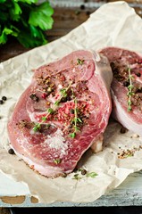 Raw turkey steaks with spices on parchment and iron background