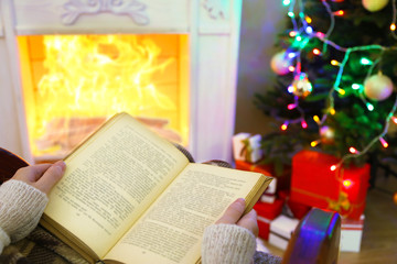 Woman holding book in front of fireplace