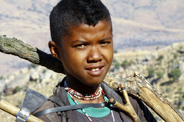 Hard working poor boy carrying a tree trunk - MADAGASCAR
