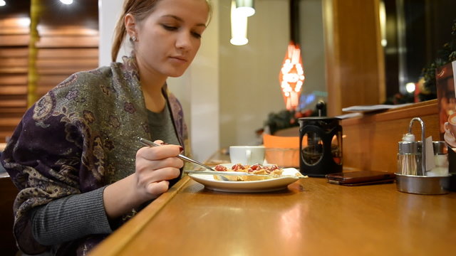 Girl eats tartlet with raspberries in a bar, restaurant 