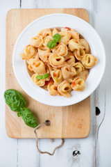 Tortellini with tomato sauce and green basil, above view