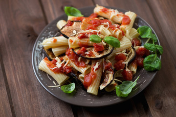 Ceramic plate with pasta alla Norma on a rustic wooden surface