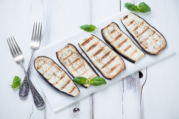 Grilled aubergine slices over white wooden background, close-up