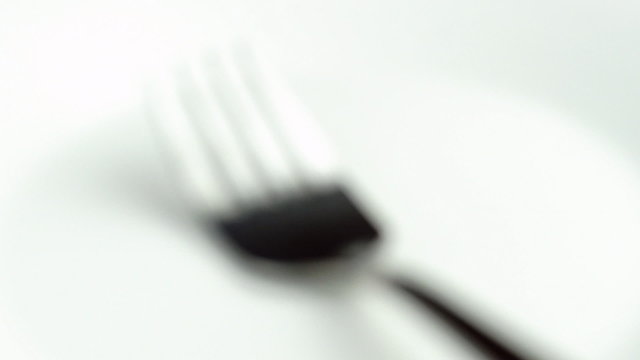 Zooming towards blurred macro of silver kitchen fork