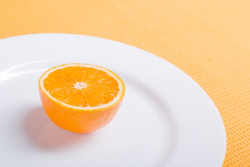 sliced ripe appetizing orange on a white plate on a yellow napki