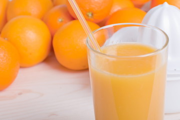 Orange fresh juice beside delicious ripe oranges on the table
