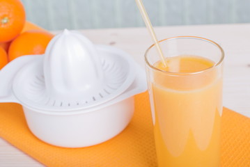 Orange fresh juice beside delicious ripe oranges on the table