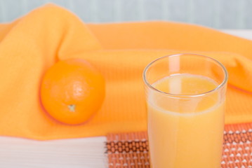 Orange fresh juice beside delicious ripe oranges on the table