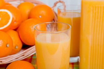 Orange fresh juice beside delicious ripe oranges on the table