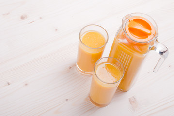 Orange fresh juice beside delicious ripe oranges on the table