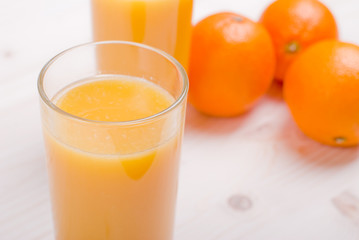 Obraz na płótnie Canvas Orange fresh juice beside delicious ripe oranges on the table