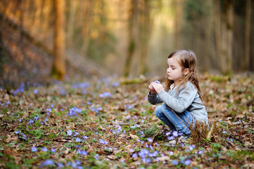 Adorable girl picking the first flowers of spring