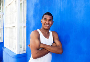 Fototapeta na wymiar Lachender Student aus Südamerika lehnt an blauer Wand