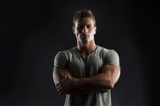Handsome muscular young man on dark with stern expression
