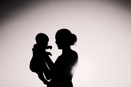 Silhouette of mother and baby at sunset