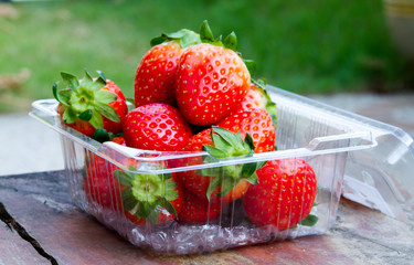 fresh strawberries on the table and inside plastic box