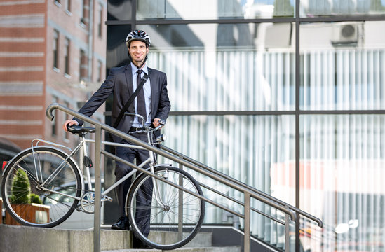 Handsome young businessman carrying bicycle down steps