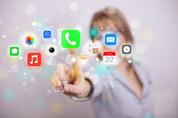 Young businesswoman pressing colorful mobile app icons with boke