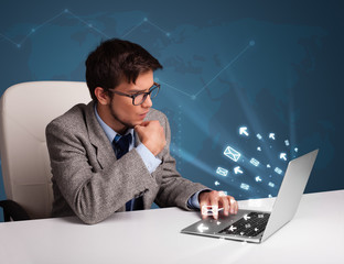 Young man sitting at dest and typing on laptop with message icon