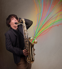 Attractive musician playing on saxophone while colorful abstract