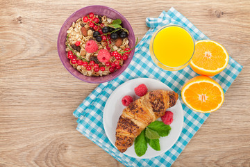 Healthy breakfast with muesli, berries, orange juice and croissa
