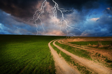 Naklejka na ściany i meble Thunderstorm with lightning in green meadow.