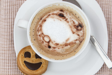 Cup of cafe au lait with smiling cookies