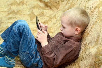teenager boy lying on the bed with a Tablet PC