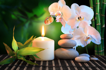 spa composition: white orchid, candle and stones in green