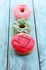 Delicious donuts with glaze on colorful wooden background
