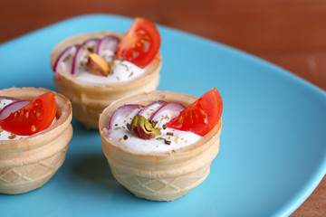 Tartlets with greens and vegetables with sauce on plate on
