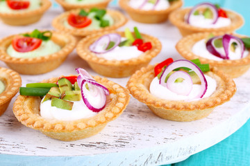 Tartlets with greens and vegetables with sauce on tray close-up