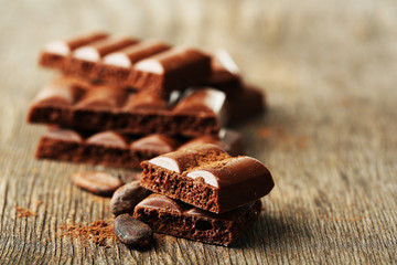 Tasty porous chocolate with cocoa beans, on wooden table