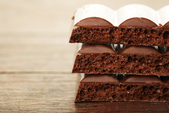 Tasty porous chocolate on wooden table