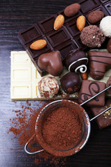 Bars of chocolate, sweet candies and strainer with cocoa