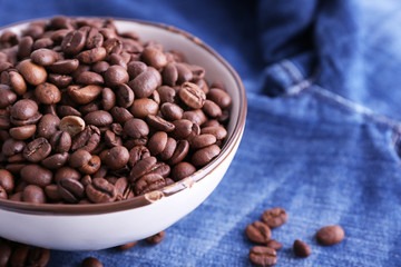 bowl of coffee beans stands on jeans background